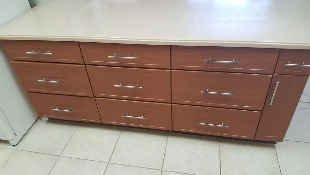 Wooden cabinet with six drawers and silver handles below a white countertop.
